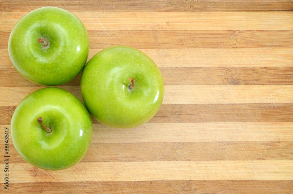green apple sit on a worn butcher block cutting board green apple sit on a worn butcher block cutting board