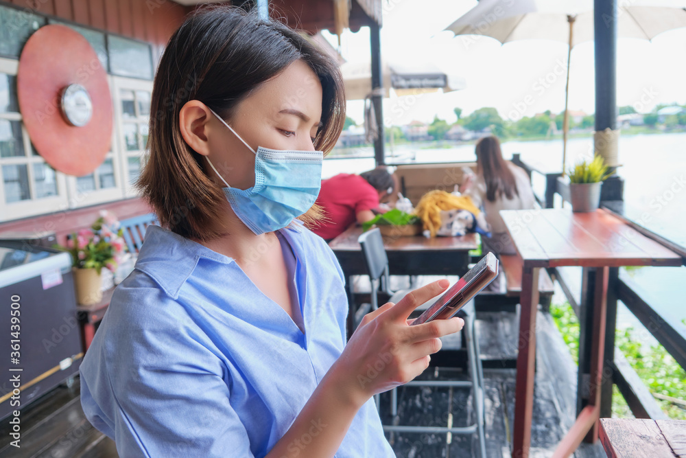 Asian young women wearing a mask and use a smartphone Asian young women wearing a mask and use a smartphone