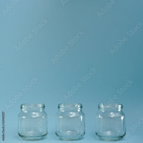 Horizontal row of three transparent jars in a blue square.