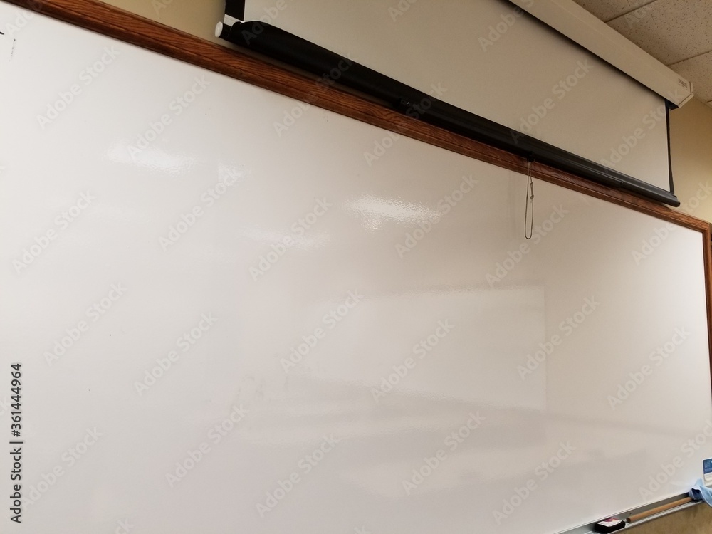 Blank whiteboard in front of classroom and projection screen Stock