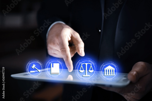 Laws, legal information and online consultation. Man using tablet, closeup. Icons over device