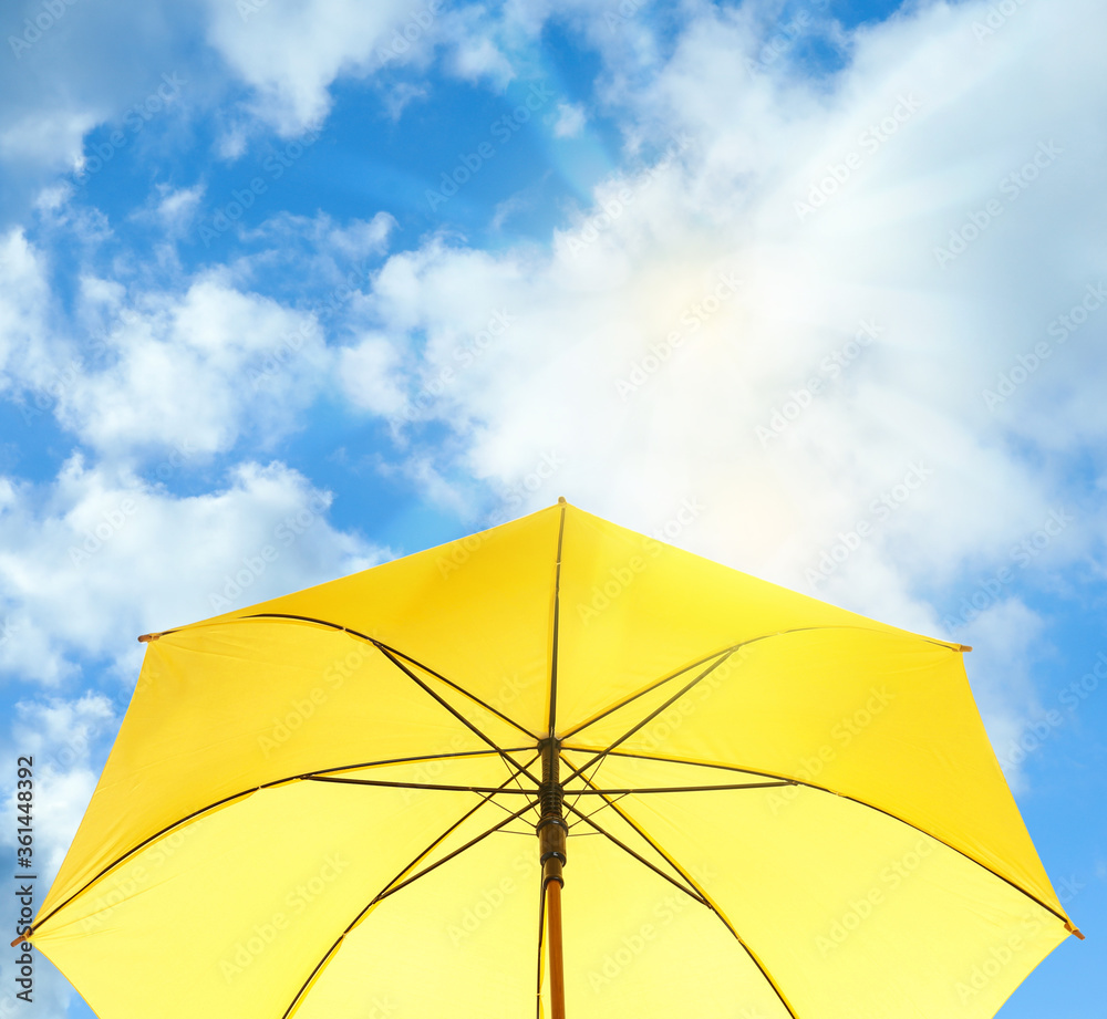 Modern yellow umbrella against blue sky. Sun protection