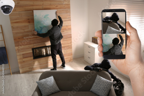Canvas Print Man monitoring situation at his house with CCTV app on smartphone, closeup