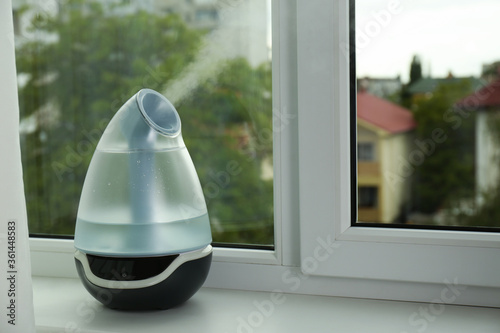 Modern air humidifier on windowsill indoors. Space for text