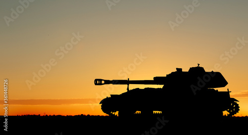 Silhouette of army tank at sunset outdoors. Military machinery