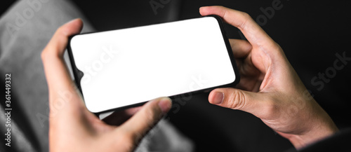 Hand holds smartphone in the night.