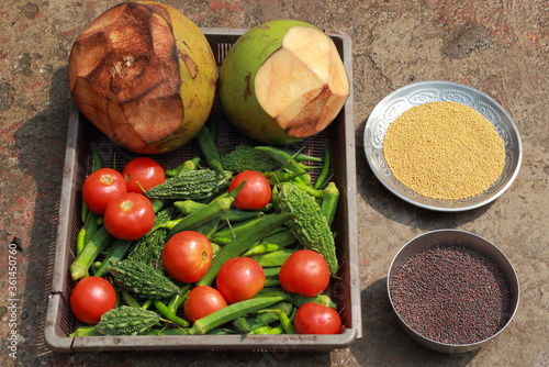 tender coconut tomato bitter gourd and food grains mustard kept on tray