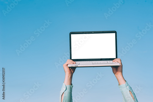 Mock up laptop in the hands of a man, against the sky.