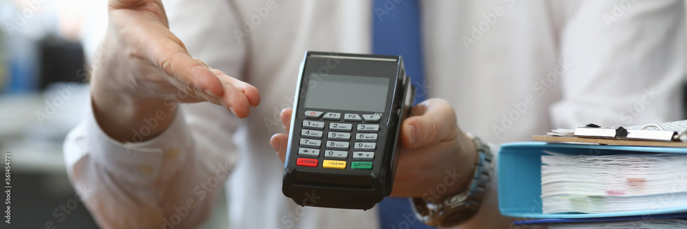 Man holds his hand wireless terminal for payment. Bank employee offers to install a wireless terminal for business. Providing customers with more convenient way to make settlements Man holds his hand wireless terminal for payment. Bank employee offers to install a wireless terminal for business. Providing customers with more convenient way to make settlements