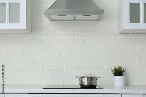 Saucepot on induction stove in stylish kitchen interior photo