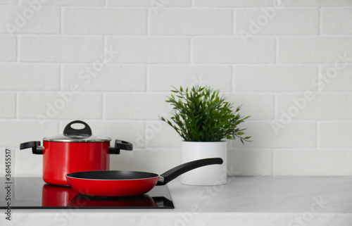 Saucepot and frying pan on induction stove in kitchen © New Africa