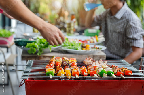 Assorted delicious barbecue with meat and vegetable on the stove over men in party background.