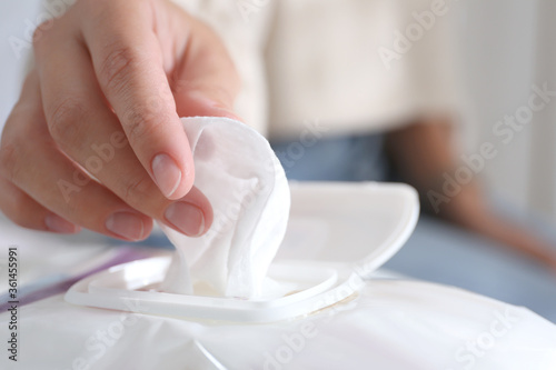 Woman taking wet wipe out of pack against blurred background  closeup