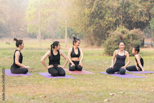 Group of asian women having rest after practices yoga. Women sitting and talking in outdoor park.