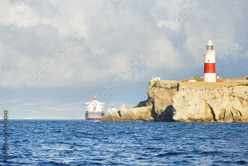 Trinity lighthouse at the rocky shore (cliffs) of the Europa Point. British Overseas Territory of Gibraltar, Mediterranean sea. National landmark, sightseeing, travel destination, famous place, travel