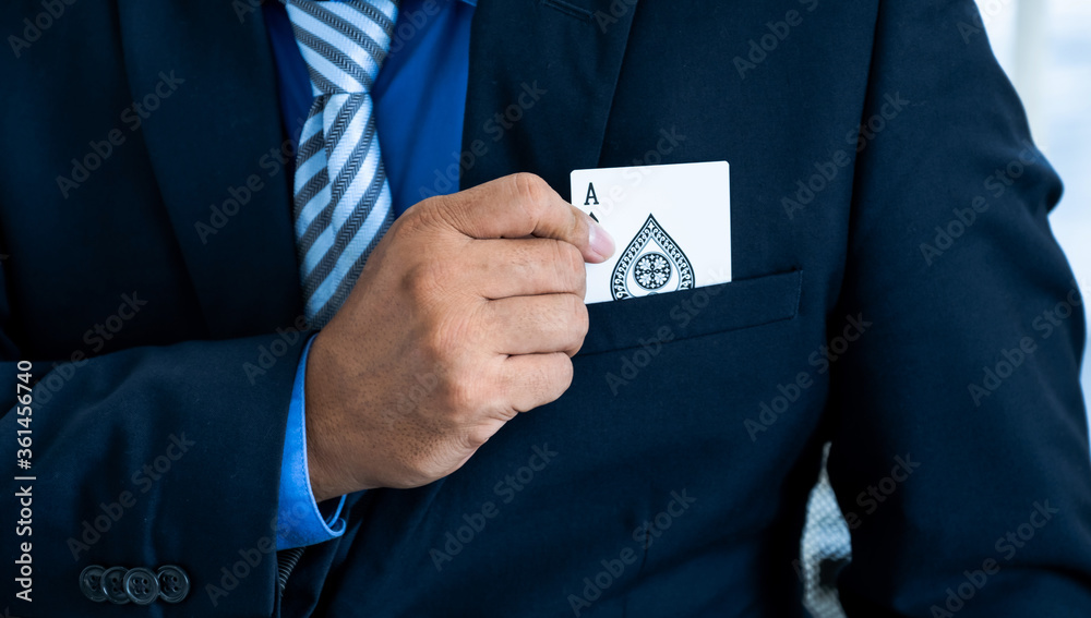 A business man's hand is holding an ace card out of a suit pocket, at a magic poker show. Gambling concept A business man's hand is holding an ace card out of a suit pocket, at a magic poker show. Gambling concept
