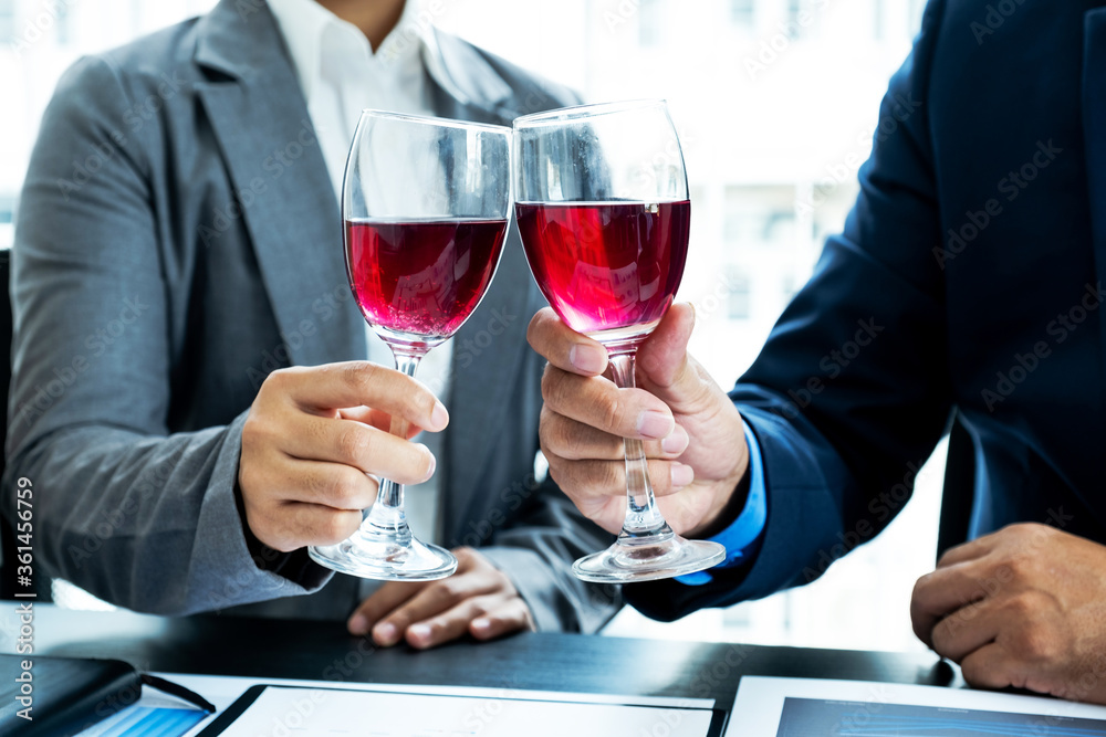 Two business executives people, businesswomen, and businessman in a suit is bumping into a glass of wine celebrating success at the office desk. After the meeting Two business executives people, businesswomen, and businessman in a suit is bumping into a glass of wine celebrating success at the office desk. After the meeting