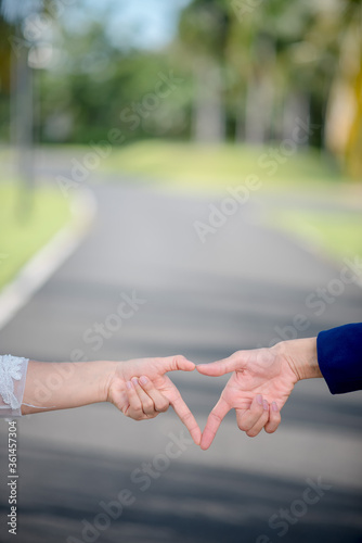 Women and men make heart-shaped hand on the street.