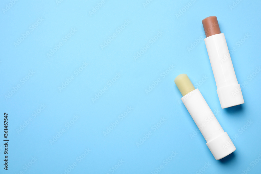 Hygienic lipsticks on light blue background, flat lay. Space for text Hygienic lipsticks on light blue background, flat lay. Space for text