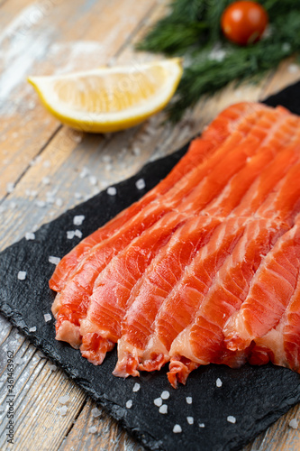 Close up of red trout slices on a dark stone background, appetizing photo for a market catalogue