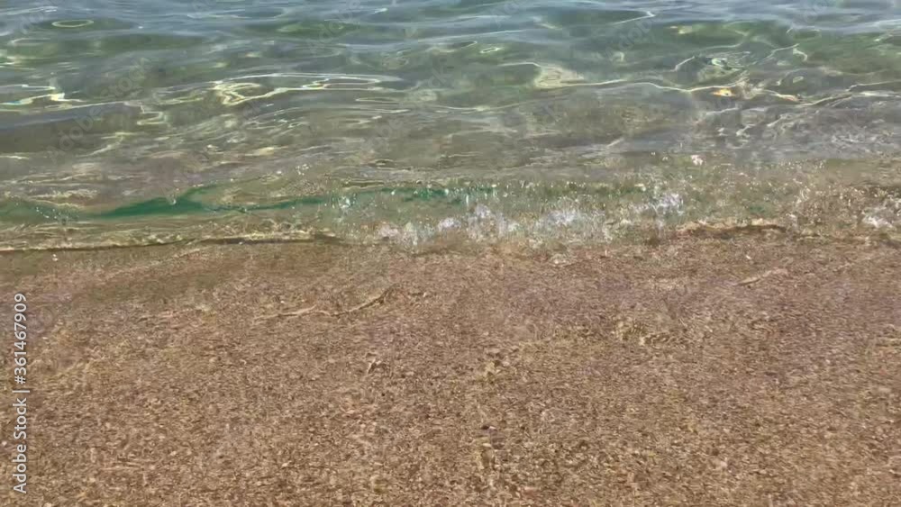 Sea level closeup of endless crashing waves onto shore with golden sand seafloor in 4k
