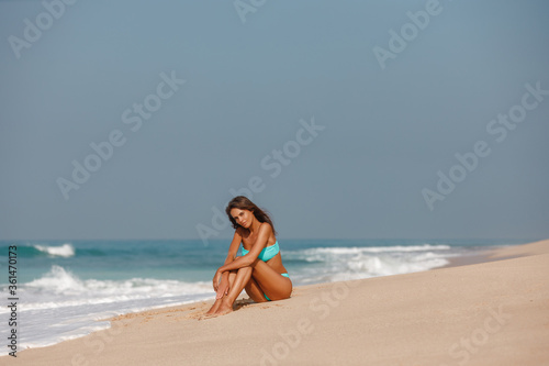 Pretty model woman in blue  swimsuit enjoying summer vacation  sit on the sand near the sea Beach vacation
