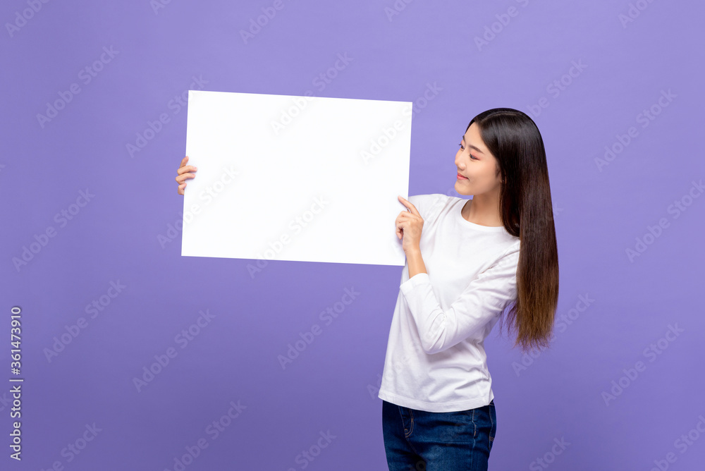 Smiling cheerful Asian woman looking to blank paper isolated on colorful purple background Smiling cheerful Asian woman looking to blank paper isolated on colorful purple background