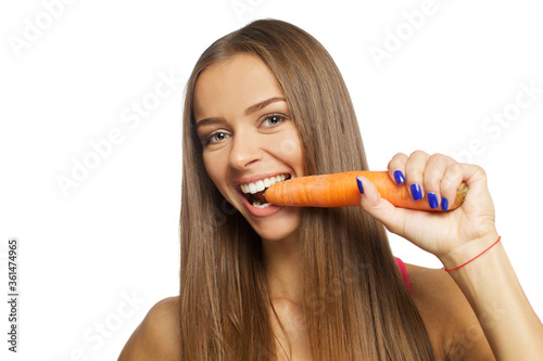 Beautiful sexy young woman eating carrot isolated on white background