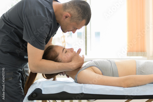 Osteopath treatment in the cabinet - the medical master holding the neck of young woman