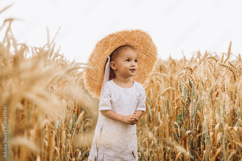 pretty cute baby girl with a beautiful smile wearing summer straw hat in a walk in the wheat fields. selective focus. family, people concept pretty cute baby girl with a beautiful smile wearing summer straw hat in a walk in the wheat fields. selective focus. family, people concept