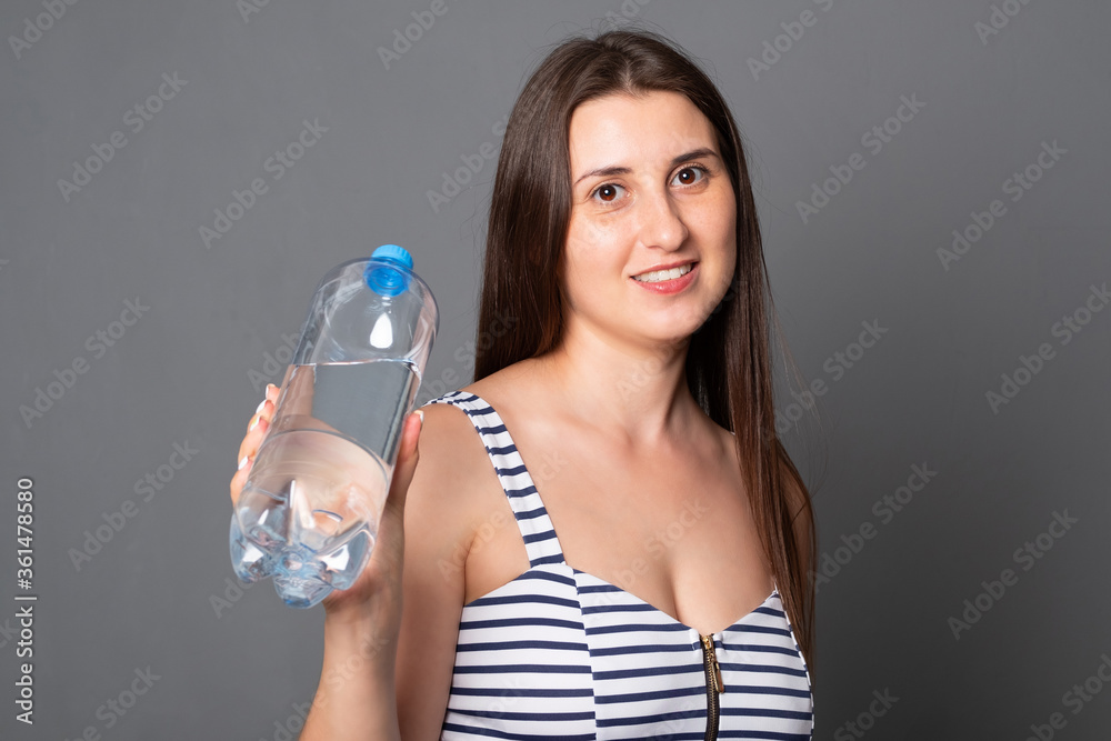 Happy woman holds a bottle of water. Portrait of a young woman drinks water from a bottle. Happy woman holds a bottle of water. Portrait of a young woman drinks water from a bottle.