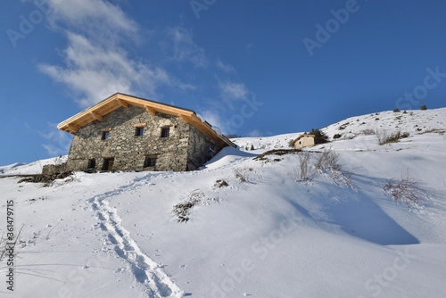 traditional alpine chalet at the top of snowy mountain under blue sky © coco
