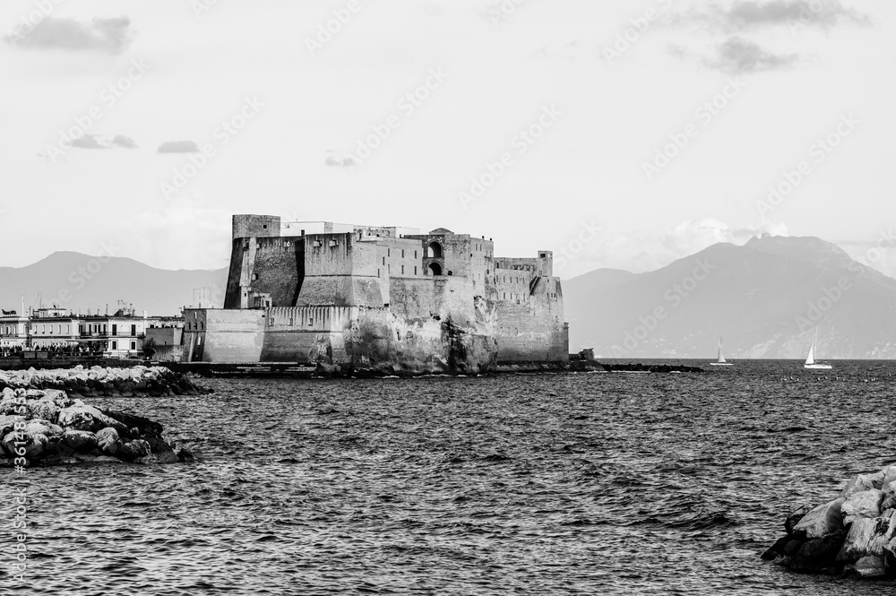 Ovo Castle in Naples, Italy on the peninsula of Megaride in the Gulf of Naples Naples with mount Vesuvius in the background in black and white