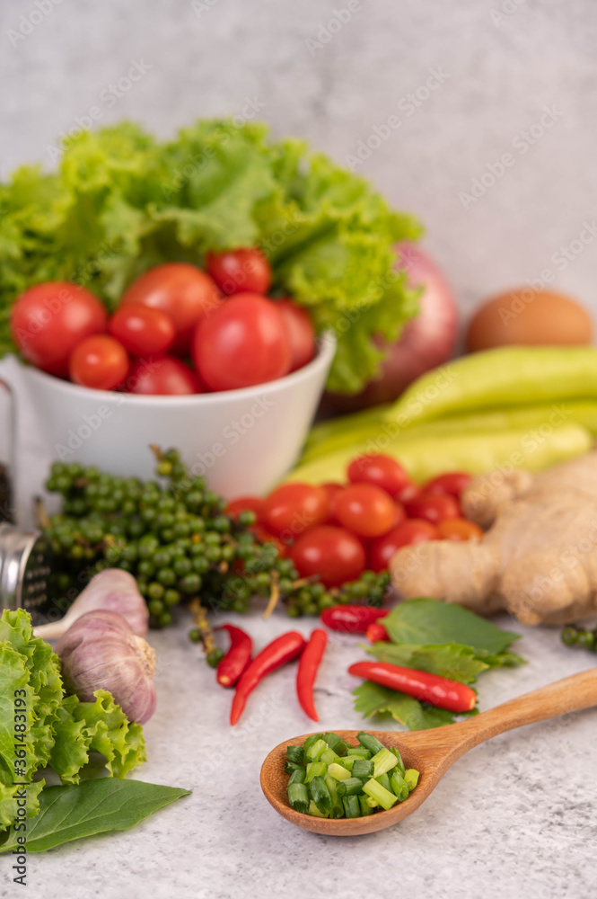 Lettuce and tomatoes in a white cup with sliced onions and fresh peppers on the cement floor. Lettuce and tomatoes in a white cup with sliced onions and fresh peppers on the cement floor.
