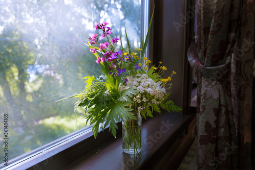 beautiful summer bouquet of wild flowers on the windowsill at home