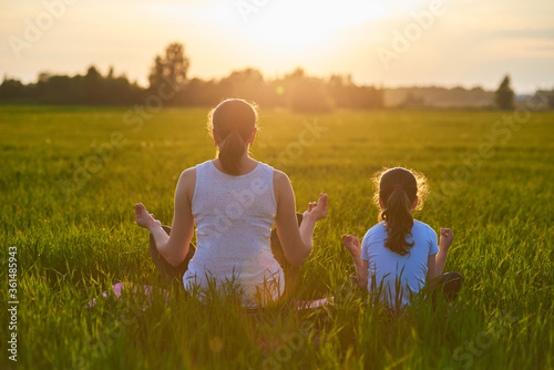 a mother and her child do yoga in the fresh air. The concept of a healthy lifestyle. Outdoor recreation. Meditation and yoga classes