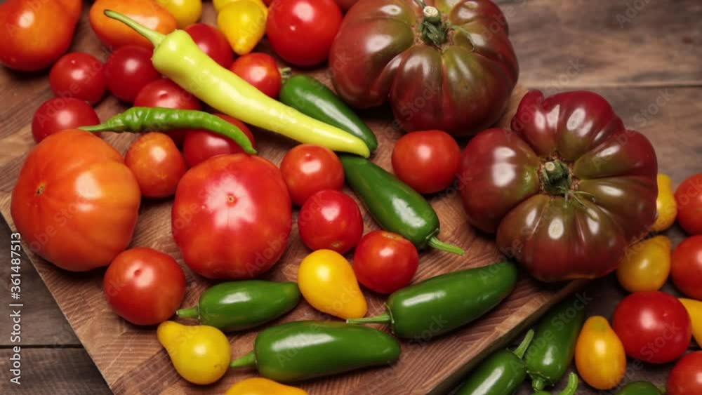 Flat lay on rustic aged pallet wood Cherokee purple tomato Jalapeno pepper red and yellow tomatoes cayenne and yellow pepper with hardwood cutting board. Flat lay on rustic aged pallet wood Cherokee purple tomato Jalapeno pepper red and yellow tomatoes cayenne and yellow pepper with hardwood cutting board.