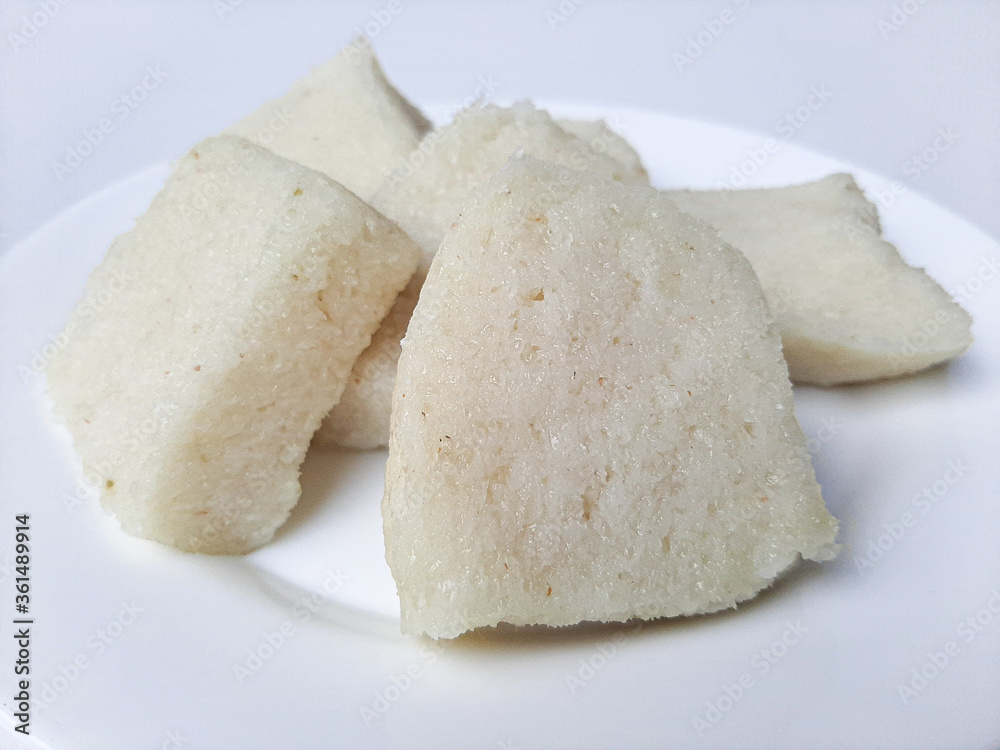 Jadah ketan, is a traditional snack from Indonesia. Made from sticky rice and grated coconut. Commonly served as tea time snack. On a white plate, isolated in white background