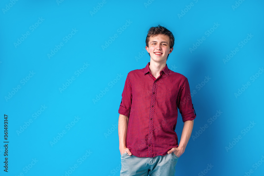 Full-length portrait of a young man standing on a blue background. Full-length portrait of a young man standing on a blue background.