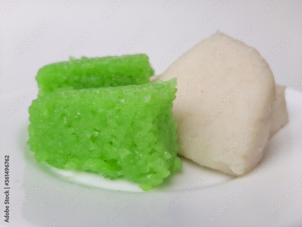Jadah ketan (white) and wajik ketan (green), two traditional snacks from Indonesia. Made from sticky rice. On a white plate, isolated in white background