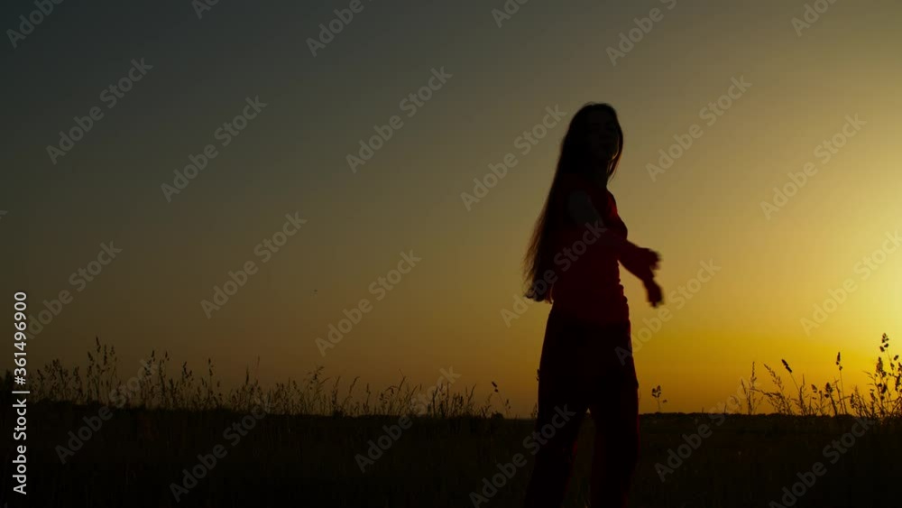 Joyful carefree long hair woman with arms outstretched relaxing in summer nature, spinning around on meadow, silhouetted by sunsetting sun during vacations in countryside, being free and happy. Joyful carefree long hair woman with arms outstretched relaxing in summer nature, spinning around on meadow, silhouetted by sunsetting sun during vacations in countryside, being free and happy.