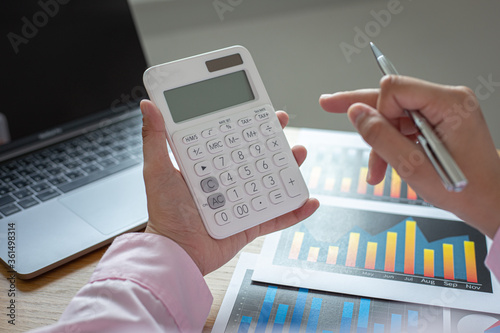 Asian business men calculate finances using graphs and calculators in the office.