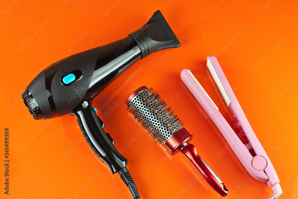 Obraz premium Hairdryer, comb, scissors isolated on a orange background. Layout for design. Mockup