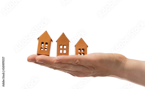 Three paper houses on the open palm of woman hand. On white isolated background. Concept of rent, search, purchase real estate.