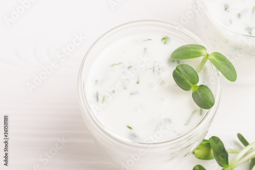 Green smoothie milkshake with the addition of fresh microgreen herb sprouts in a glass beaker on a white background. photo