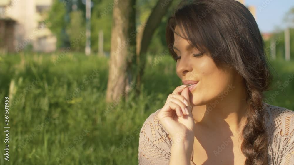 Close up portrait of a beautiful smiling woman eating cherry. Picnic on the grass in the park. Relaxation and pleasure Close up portrait of a beautiful smiling woman eating cherry. Picnic on the grass in the park. Relaxation and pleasure