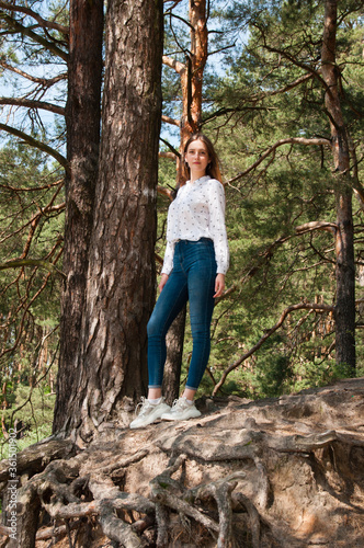 Very beautiful young woman in coniferous forest in summer in hot sunny weather