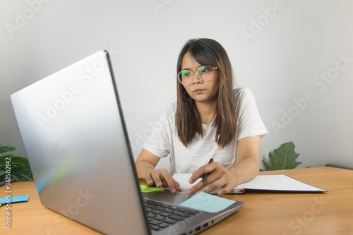 Valokuva Asian woman wearing a white T-shirt and wearing glasses to work at home with ser