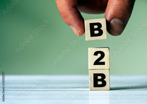 The hand puts the cube block with the inscription B2B. Business to business concept background.