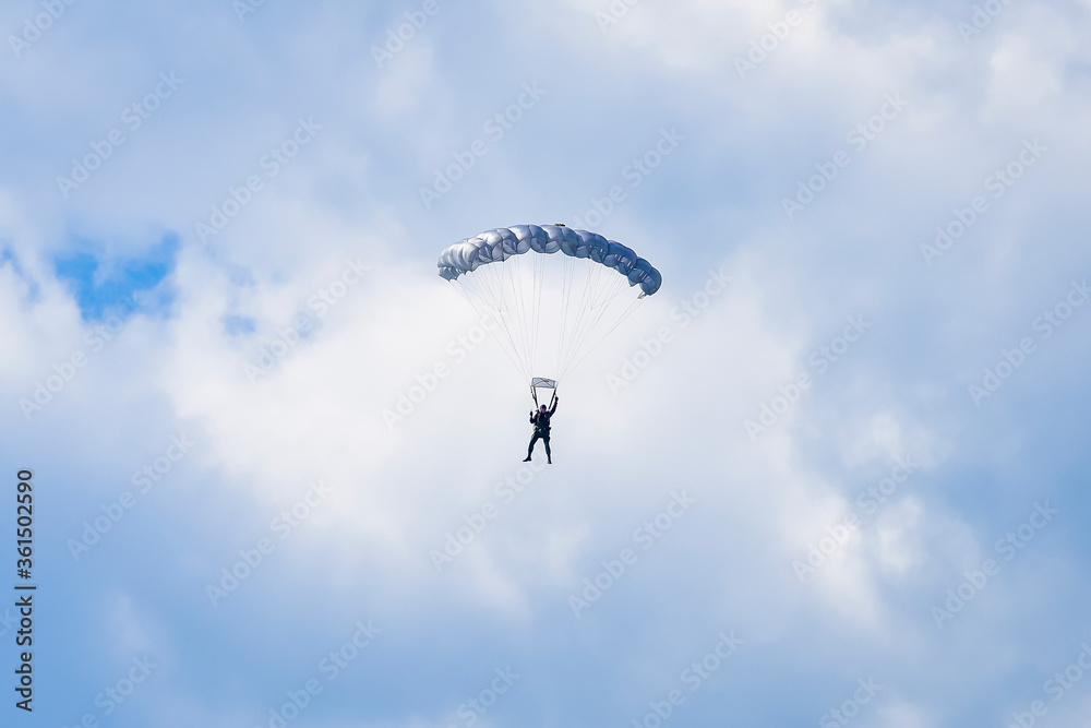 Skydiver and colorful parachute on the blue sky Skydiver and colorful parachute on the blue sky